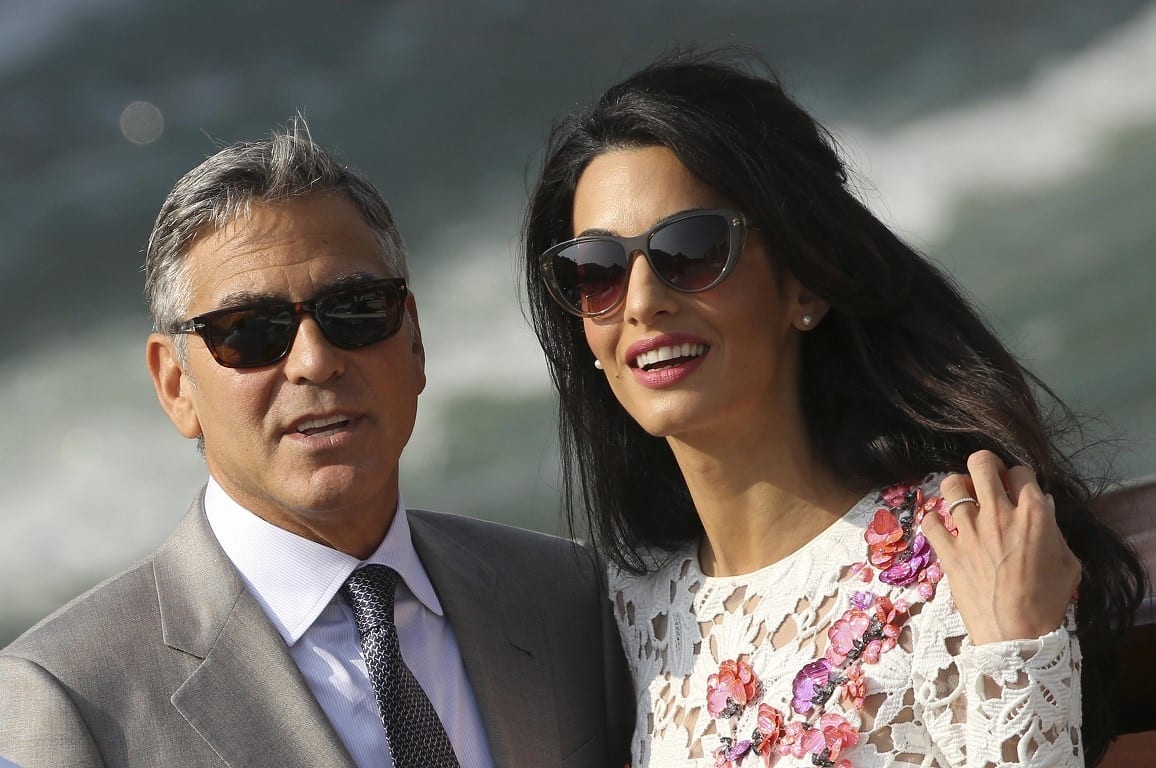 U.S. actor George Clooney and his wife Amal Alamuddin travel on a water taxi at the Grand Canal in Venice September 28, 2014. The world's most famous bachelor broke a vow to remain single on Saturday and married human rights lawyer Alamuddin during a weekend of lavish celebrations in Venice. The Italian city of gondolas and palazzi looked like Hollywood on the Adriatic as A-list guests cruised between luxury hotels for the extravaganza, billed as the party of the year even as details were kept largely secret. REUTERS/Alessandro Bianchi (ITALY - Tags: ENTERTAINMENT PROFILE)