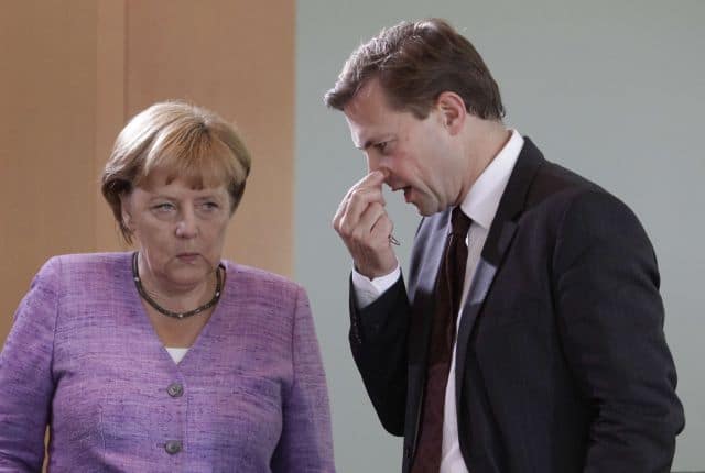 German Chancellor Angela Merkel chats with German government spokesman Steffen Seibert (R) before the weekly cabinet meeting in Berlin, September 19, 2012. REUTERS/Tobias Schwarz (GERMANY - Tags: POLITICS)