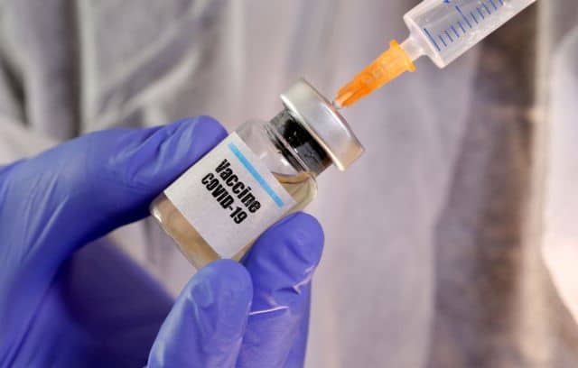 FILE PHOTO: A woman holds a small bottle labelled with a "Vaccine COVID-19" sticker and a medical syringe in this illustration taken April 10, 2020. REUTERS/Dado Ruvic/Illustration/File Photo
