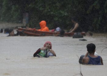 A man uses plastic containers to keep himself afloat as he crosses flooded road in Marikina, Philippines, due to Typhoon Vamco on Thursday, Nov. 12, 2020. The typhoon swelled rivers and flooded low-lying areas as it passed over the storm-battered northeast Philippines, where rescuers were deployed early Thursday to help people flee the rising waters. (AP Photo/Aaron Favila)