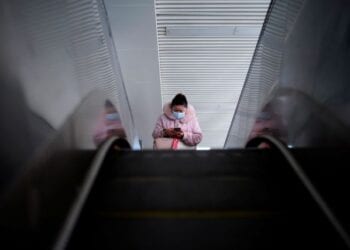 A woman wearing a mask rides on an escalator, almost a year after the start of the coronavirus disease (COVID-19) outbreak, in Wuhan, Hubei province, China December 17, 2020. REUTERS/Aly Song
