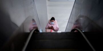 A woman wearing a mask rides on an escalator, almost a year after the start of the coronavirus disease (COVID-19) outbreak, in Wuhan, Hubei province, China December 17, 2020. REUTERS/Aly Song