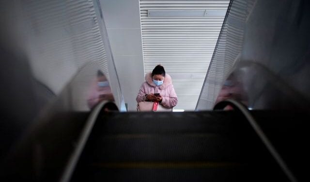 A woman wearing a mask rides on an escalator, almost a year after the start of the coronavirus disease (COVID-19) outbreak, in Wuhan, Hubei province, China December 17, 2020. REUTERS/Aly Song