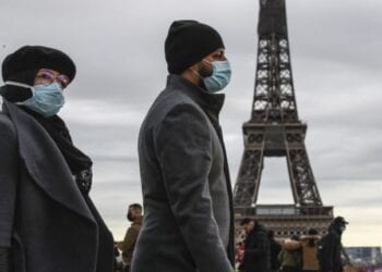 People wearing face makes to protect against the COVIS-19 walk at Trocadero plaza near Eiffel Tower in Paris, Saturday, Dec. 26, 2020. French health authorities have confirmed the country's first case of the virus variant that prompted strict new lockdown measures in Britain and global travel restrictions.(AP Photo/Michel Euler)