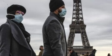 People wearing face makes to protect against the COVIS-19 walk at Trocadero plaza near Eiffel Tower in Paris, Saturday, Dec. 26, 2020. French health authorities have confirmed the country's first case of the virus variant that prompted strict new lockdown measures in Britain and global travel restrictions.(AP Photo/Michel Euler)