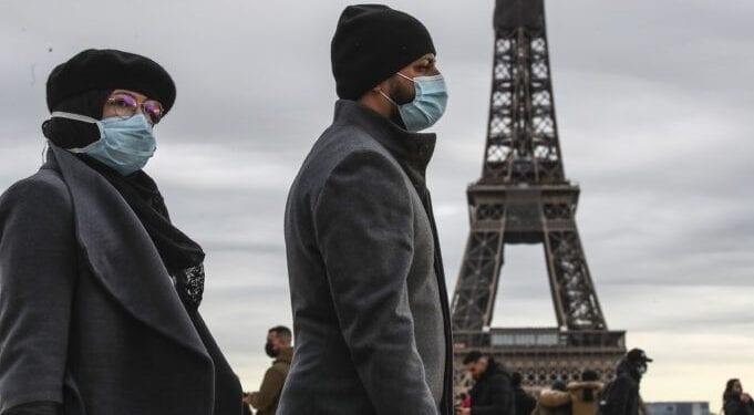 People wearing face makes to protect against the COVIS-19 walk at Trocadero plaza near Eiffel Tower in Paris, Saturday, Dec. 26, 2020. French health authorities have confirmed the country's first case of the virus variant that prompted strict new lockdown measures in Britain and global travel restrictions.(AP Photo/Michel Euler)