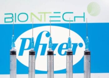 FILE PHOTO: Syringes are seen in front of displayed Biontech and Pfizer logos in this illustration taken November 10, 2020. REUTERS/Dado Ruvic/Illustration/File Photo
