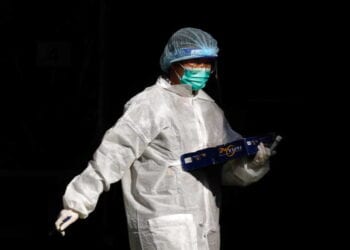 A medical worker in a protective suit walks at a makeshift community testing centre for the coronavirus disease (COVID-19), in Hong Kong, China November 30, 2020. REUTERS/Tyrone Siu