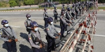 Policemen wearing protective face mask stand guard behind a road barricade, as a part of security preparations ahead of next week's opening of Myanmar's parliament in Naypyitaw, Myanmar, Friday, Jan. 29, 2021. Myanmar's election commission rejected allegations by the military that fraud played a significant role in determining the outcome of November's elections, which delivered a landslide victory to Aung San Suu Kyi's ruling party.(AP Photo/Aung Shine Oo)